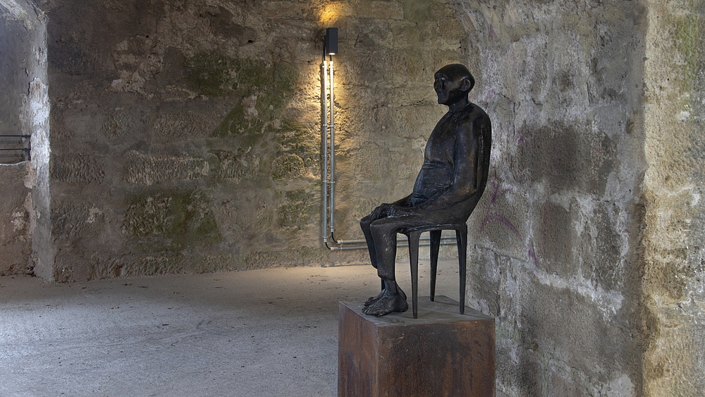 Bronzeskulptur des Künstlers Waldemar Grzimek, Darstellung eines alten Mannes, der auf einem Stuhl sitzt