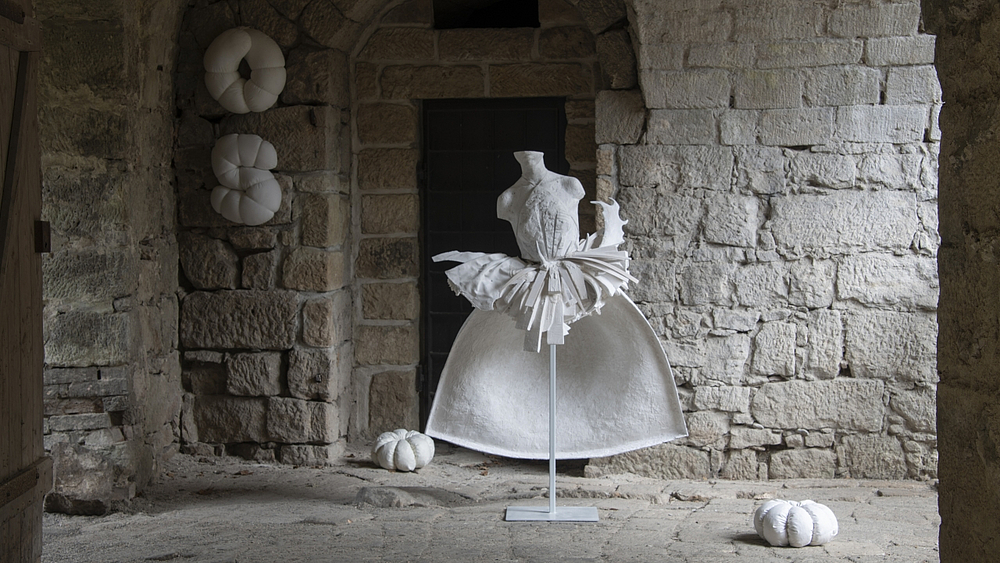 Skulptur von Katja Neubert aus verschiedenen Materialien, Darstellung eines weiblichen Torsos mit weißem Kleid auf einem Metallgestell