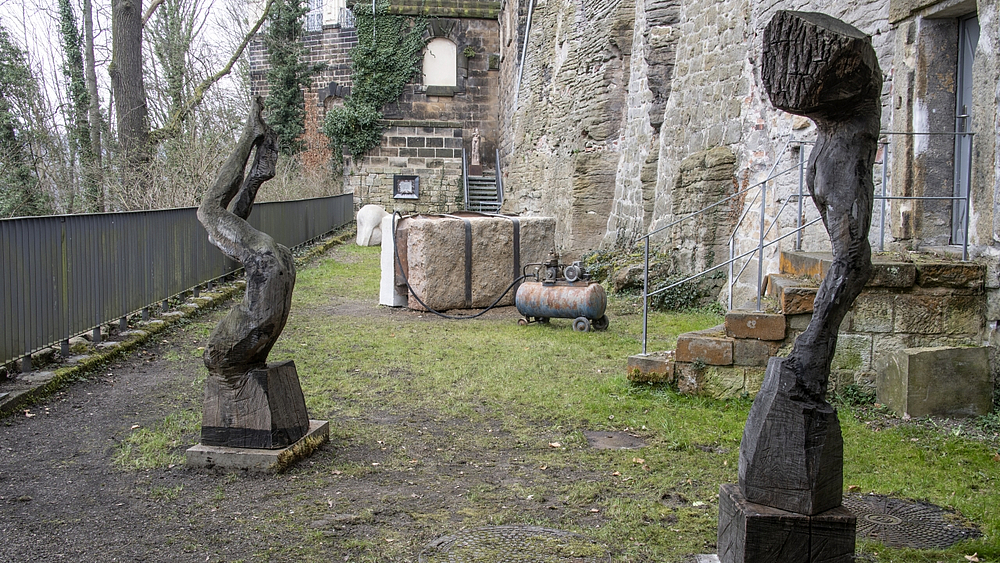 Ausstellungsansicht, im Vordergrund zwei Holzskulpturen von Katja Neubert mit der Darstellung von menschlichen Figuren