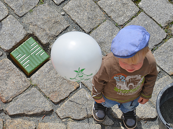 Pirnas bunte Steinepfade Kind steht mit Luftballon neben einem bunten Stein