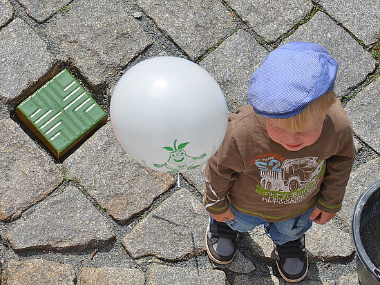 Pirnas bunte Steinepfade Kind steht mit Luftballon neben einem bunten Stein