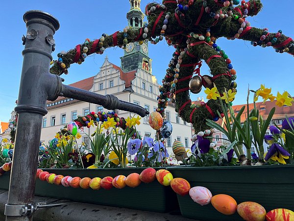 Brunnen auf dem markt ist mit einer Osterkrone geschmückt, im Hintergrund ist das Rathaus zu sehen