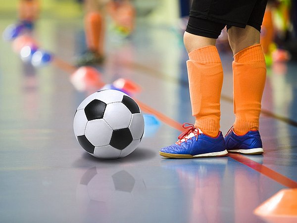 Kind spielt Fußball in einer Halle